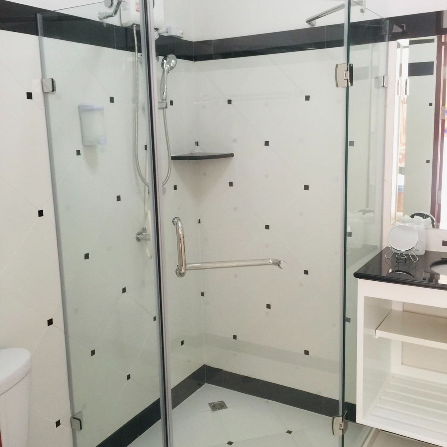 The modern white-tiled bathroom of the Deluxe Double Room at Lyndale Lodge with a glass walk-in shower