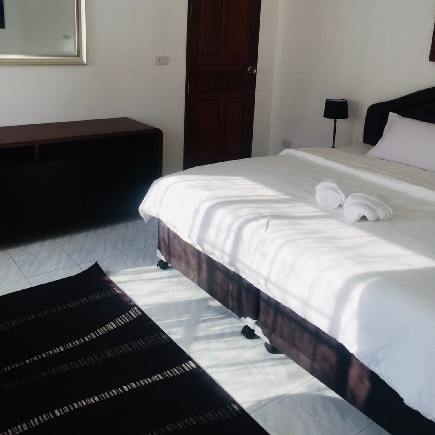 The Deluxe Double Room bed with warm wood furniture and tiled floor at Lyndale Lodge