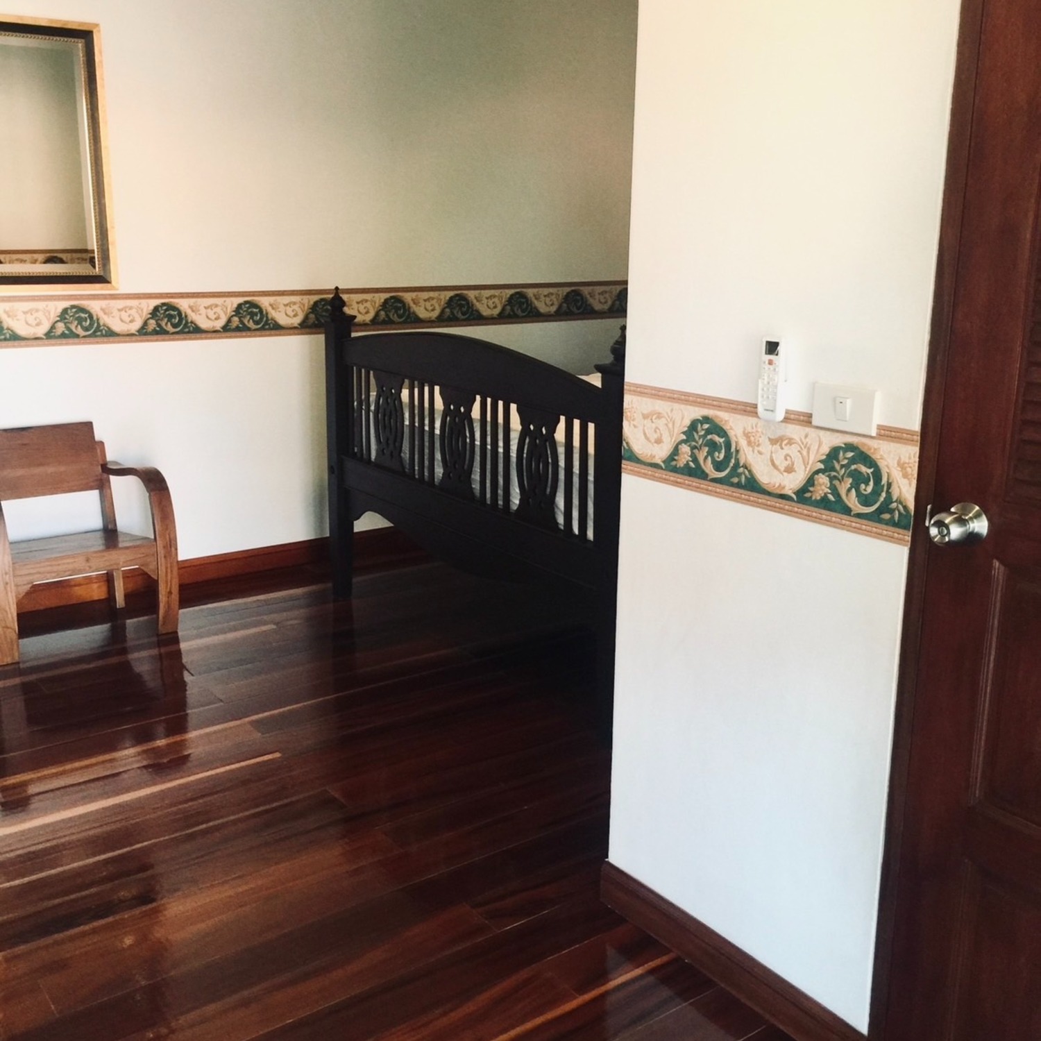 A quiet corner of the Premium Double Room at Lyndale Lodge with a wooden chair, mirror and hardwood floor