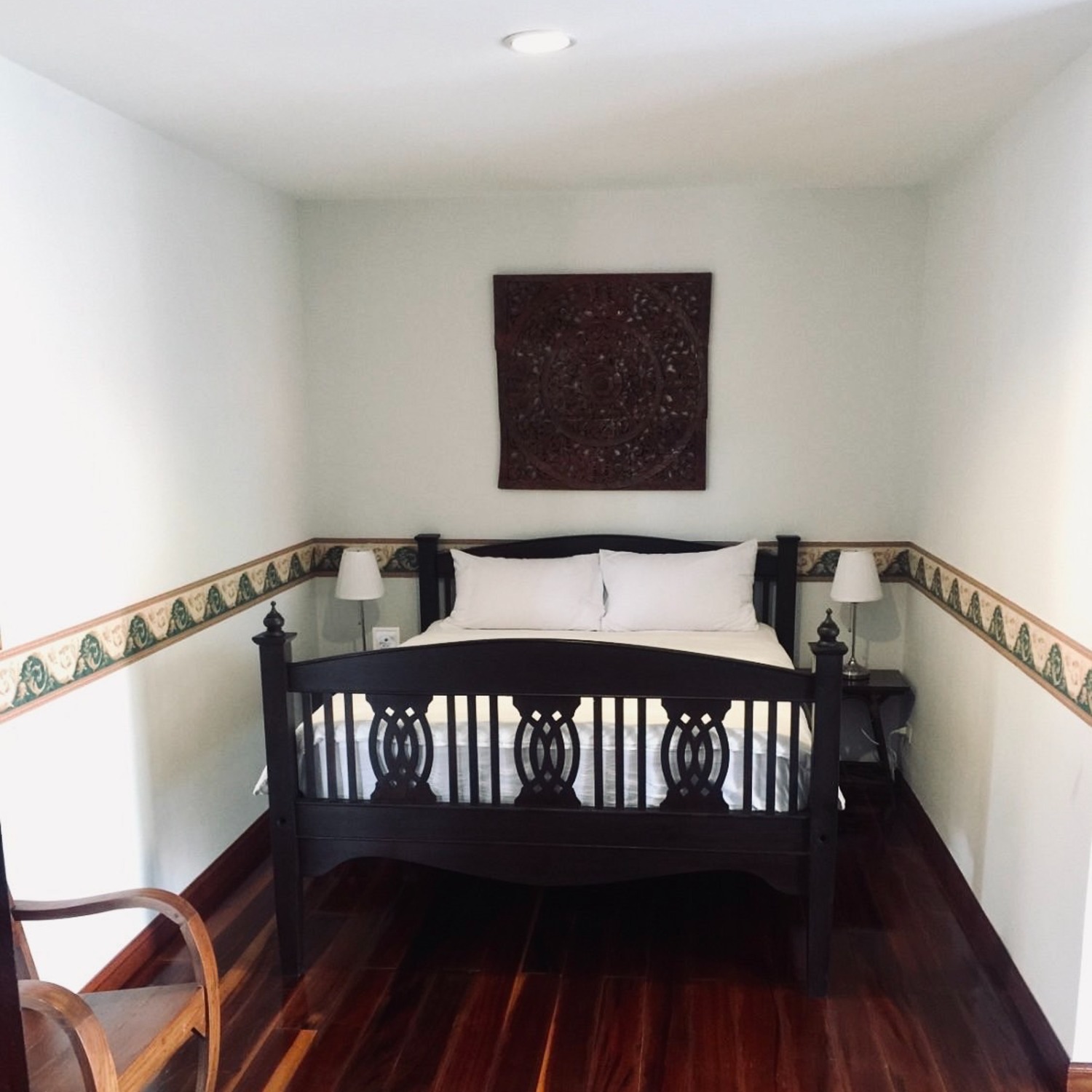 The Premium Double Room at Lyndale Lodge with a carved black bed, white bedding and polished wooden floor