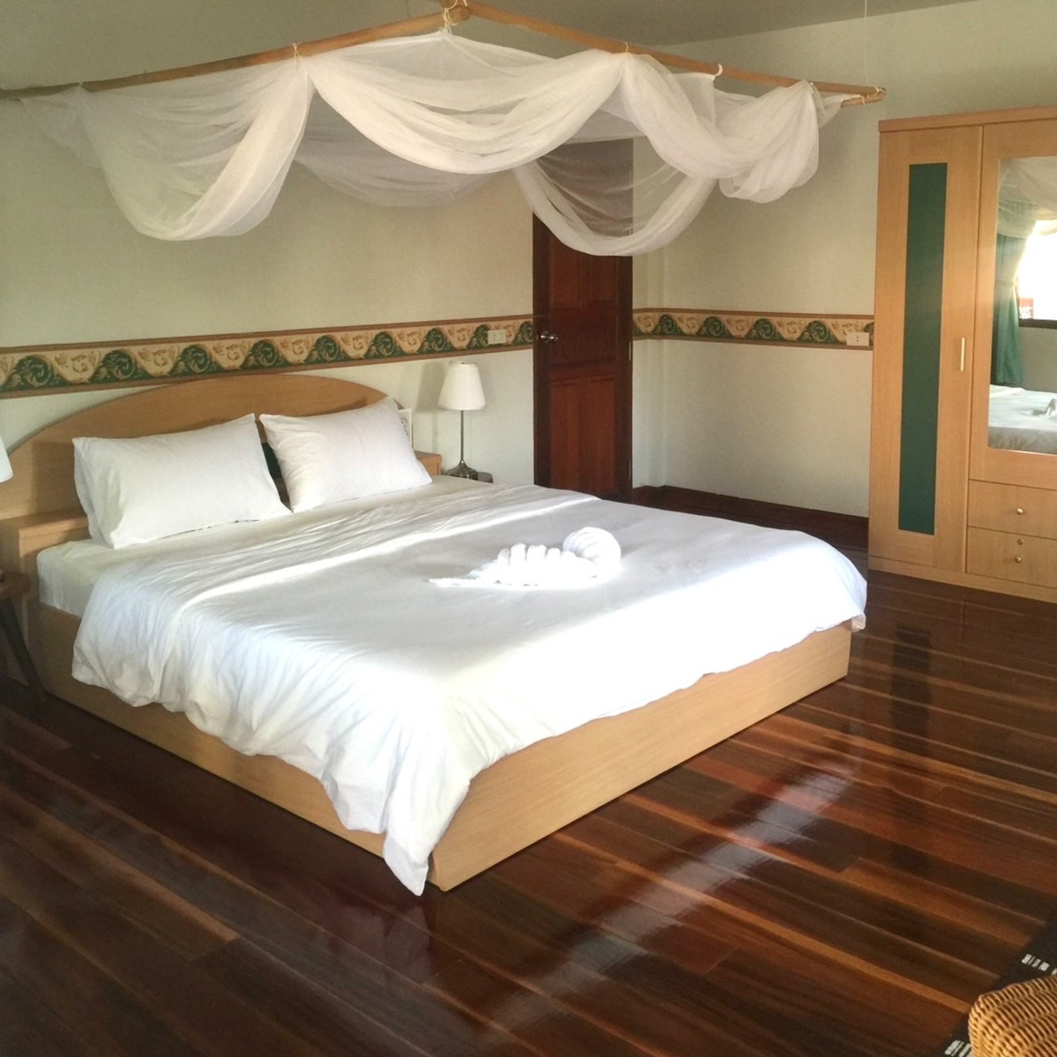 ห้องซูพีเรียร์ ของ Lyndale Lodge พร้อมเตียงคลุมมุ้งโปร่งและพื้นไม้สีเข้ม